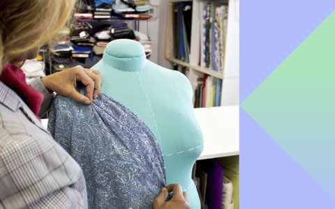 A woman's hand pinning fabric to a judy doll. 