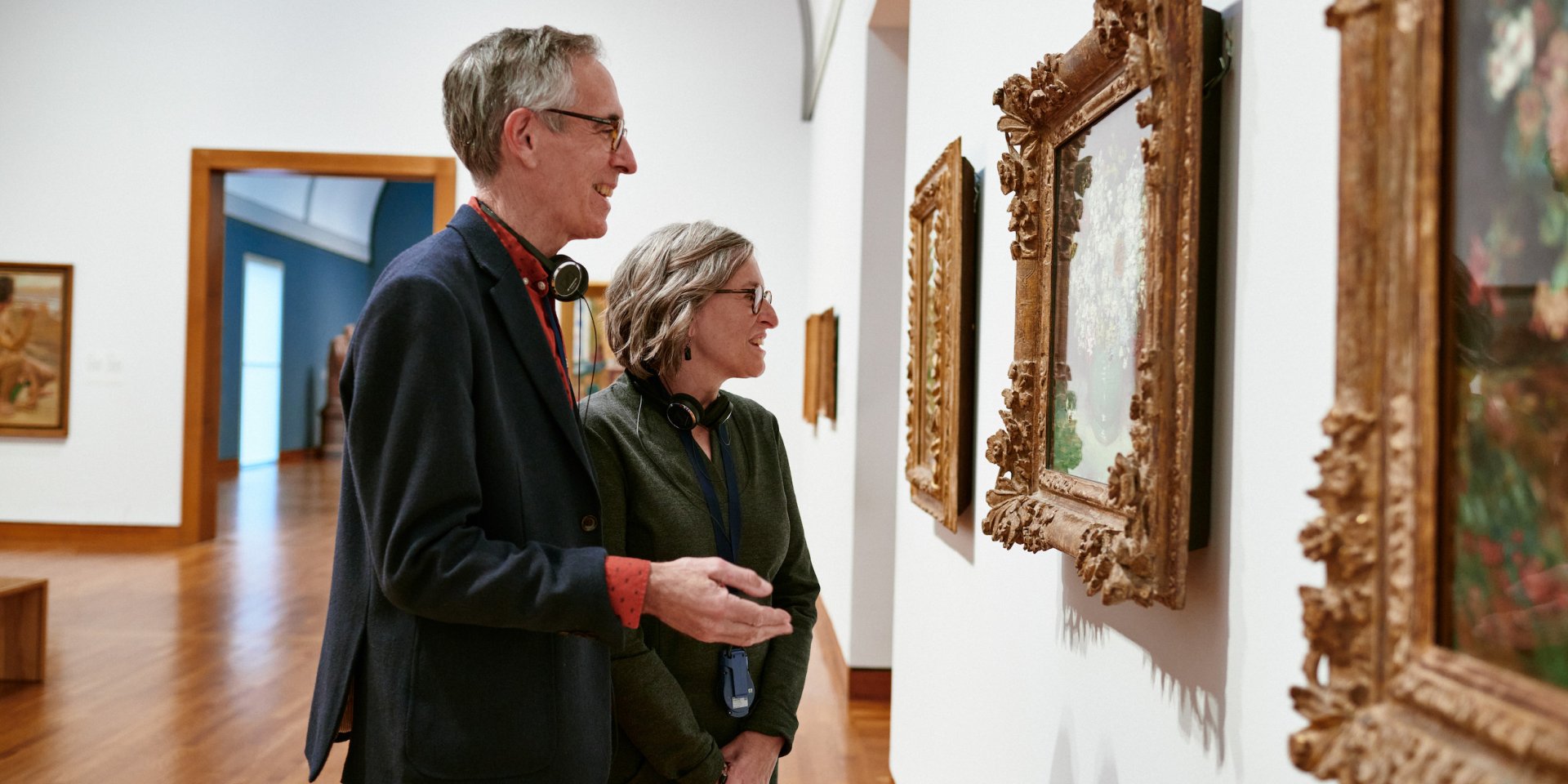 Two adult visitors examine a painting in the European galleries.