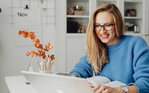 A woman is sitting in front of a laptop.